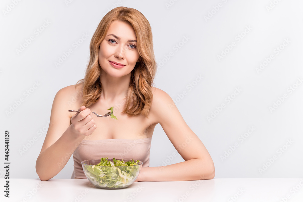 Portrait of attractive cheery healthy woman wearing nude top eating vegan vegs salad isolated over grey pastel color background Portrait of attractive cheery healthy woman wearing nude top eating vegan vegs salad isolated over grey pastel color background