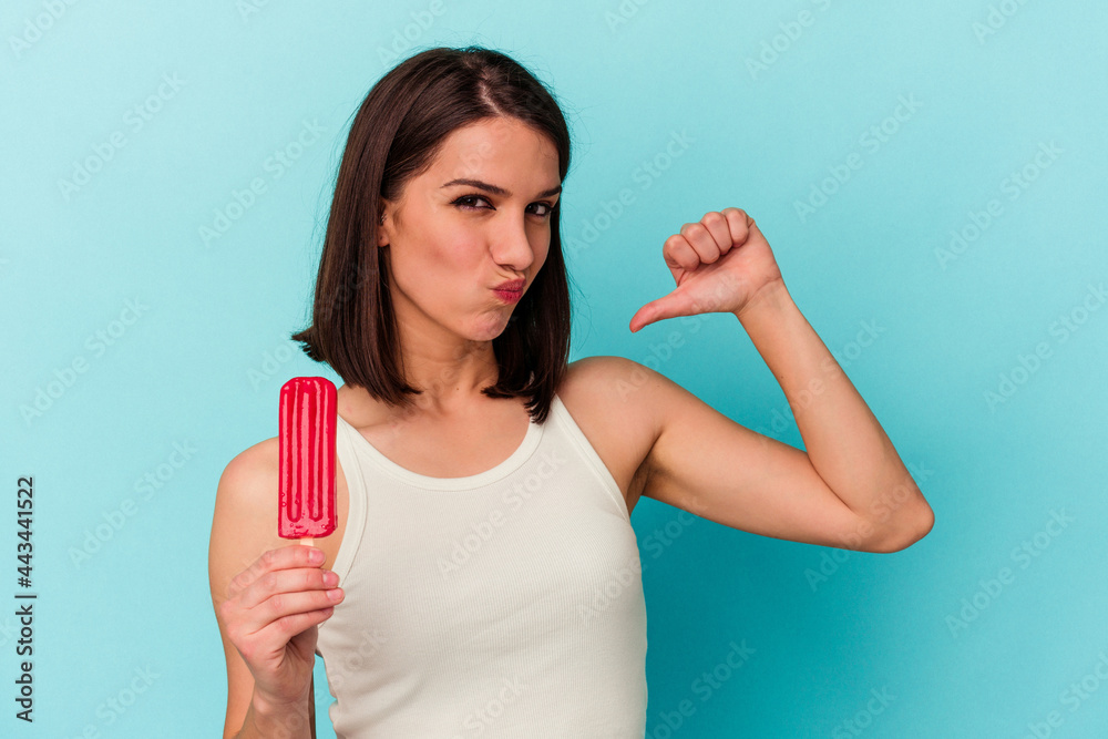 Young caucasian woman holding an ice cream isolated on blue background feels proud and self confident, example to follow. Young caucasian woman holding an ice cream isolated on blue background feels proud and self confident, example to follow.