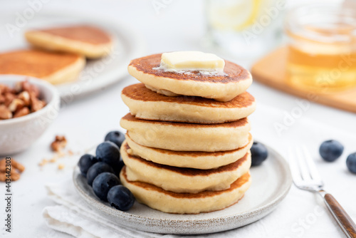 Breakfast pancakes with butter and blueberries on white plate. American cuisine food