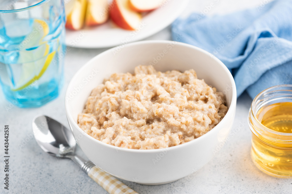 Cooked oatmeal porridge in white bowl, healthy breakfast food for dieting, fitness menu, clean eating lifestyle Cooked oatmeal porridge in white bowl, healthy breakfast food for dieting, fitness menu, clean eating lifestyle