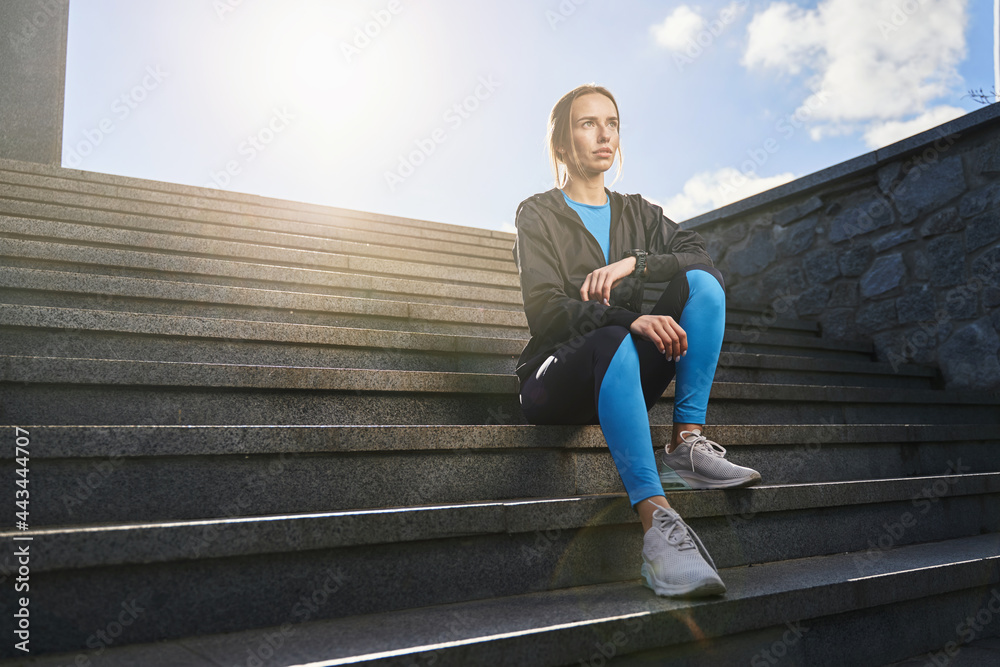 Athletic woman relaxing after running in city Athletic woman relaxing after running in city