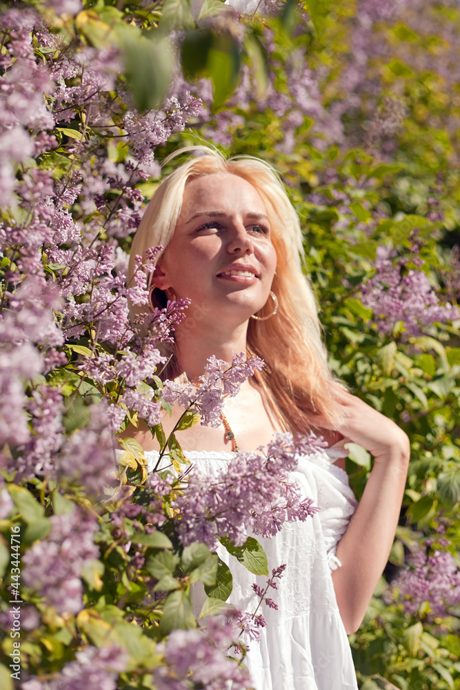 blond woman in lilac. Portrait of a beautiful and happy young woman in blossoming lilacs in park. Portrait of happiness. Positive human emotions and feelings. blond woman in lilac. Portrait of a beautiful and happy young woman in blossoming lilacs in park. Portrait of happiness. Positive human emotions and feelings.