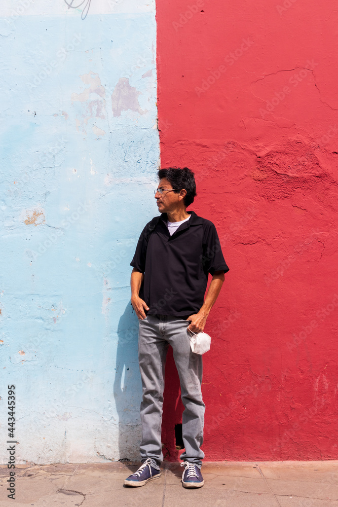 Obraz premium Hispanic man standing in front of a colorful wall in the colonial city of antigua guatemala