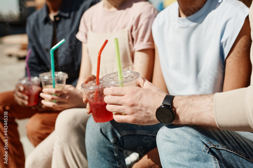 Close up of young people holding colordul cocktails while enjoying Summer in sunlight, copy space photo