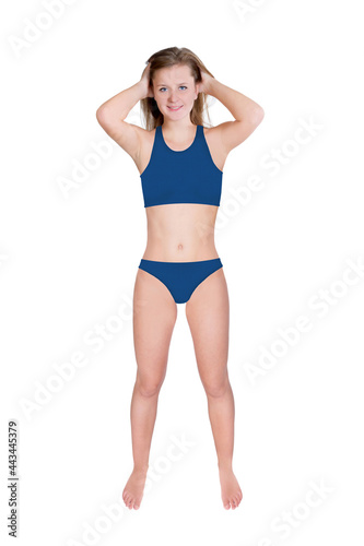 Full length portrait of a slim young woman wearing a blue bikini, isolated in front of white studio background