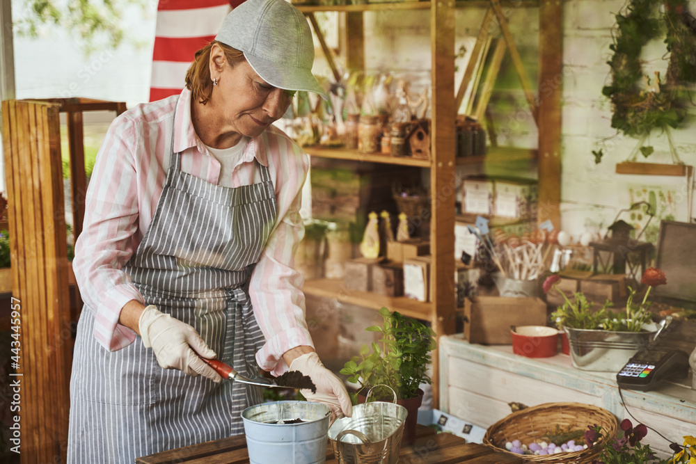Professional female florist planting seedling in shop Professional female florist planting seedling in shop