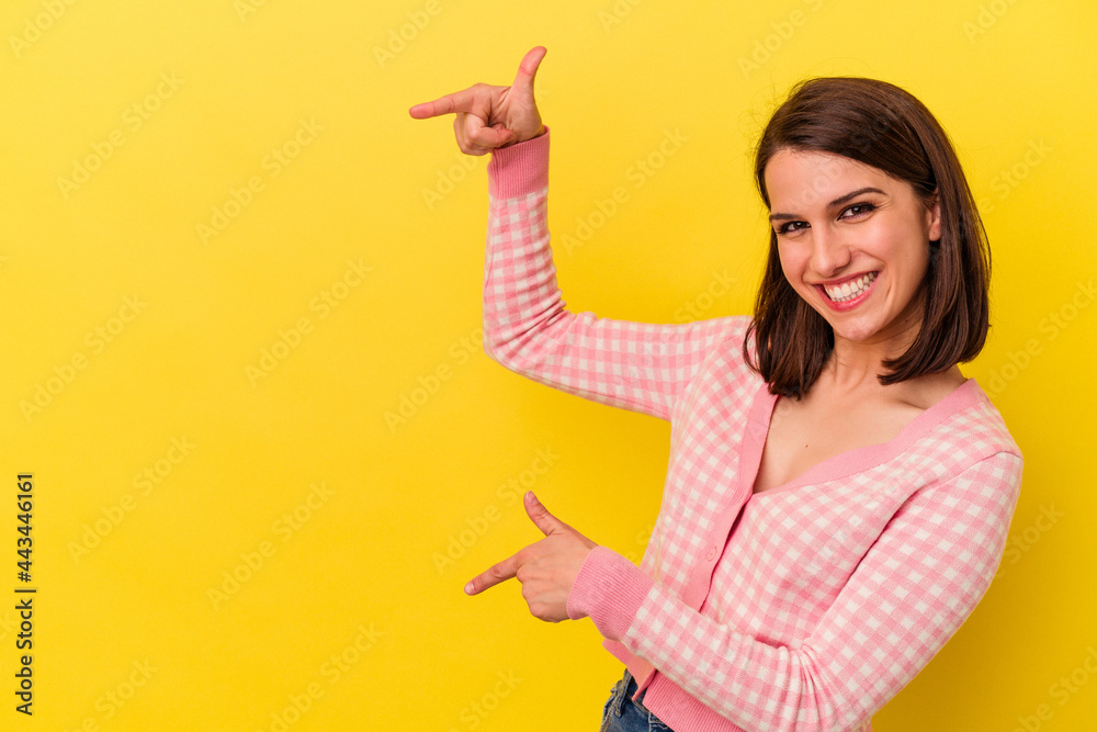 Young caucasian woman isolated on yellow background excited pointing with forefingers away. Young caucasian woman isolated on yellow background excited pointing with forefingers away.
