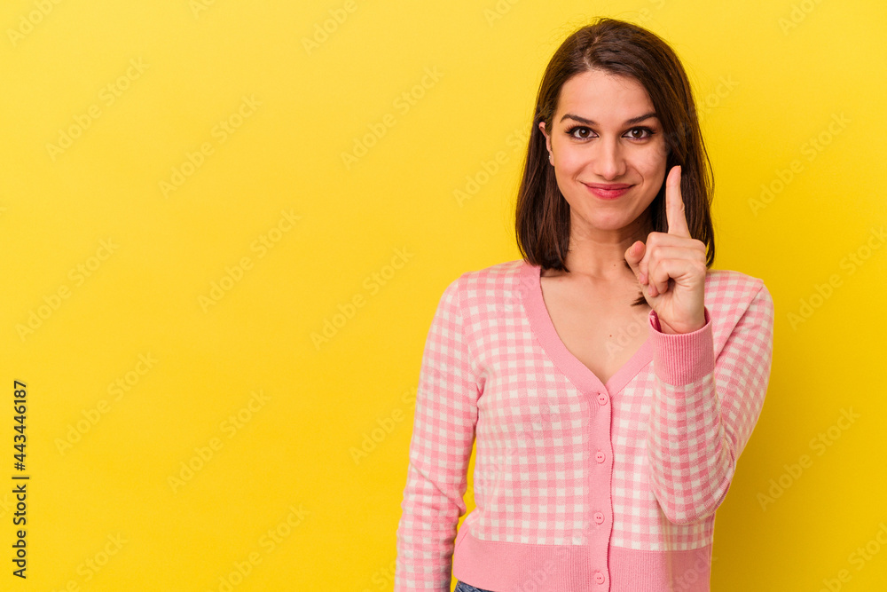 Young caucasian woman isolated on yellow background showing number one with finger. Young caucasian woman isolated on yellow background showing number one with finger.