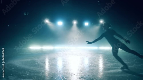 A girl skates and jumps at the ice rink in slow motion