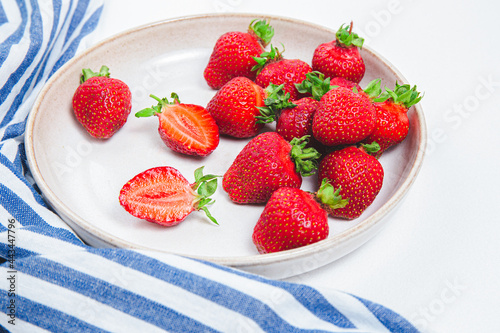 Flat plate full of fresh strawberries. Fresh ripe red strawberry background. Seasonal harvest of strawberries on a white plate and a blue towel