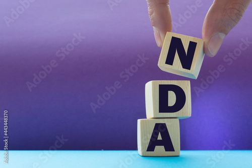NDA - non disclosure agreement - text on wooden cubes, on pink background photo