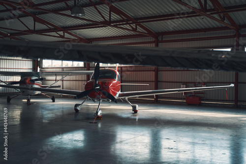 Two small red and white aircrafts in airport hangar