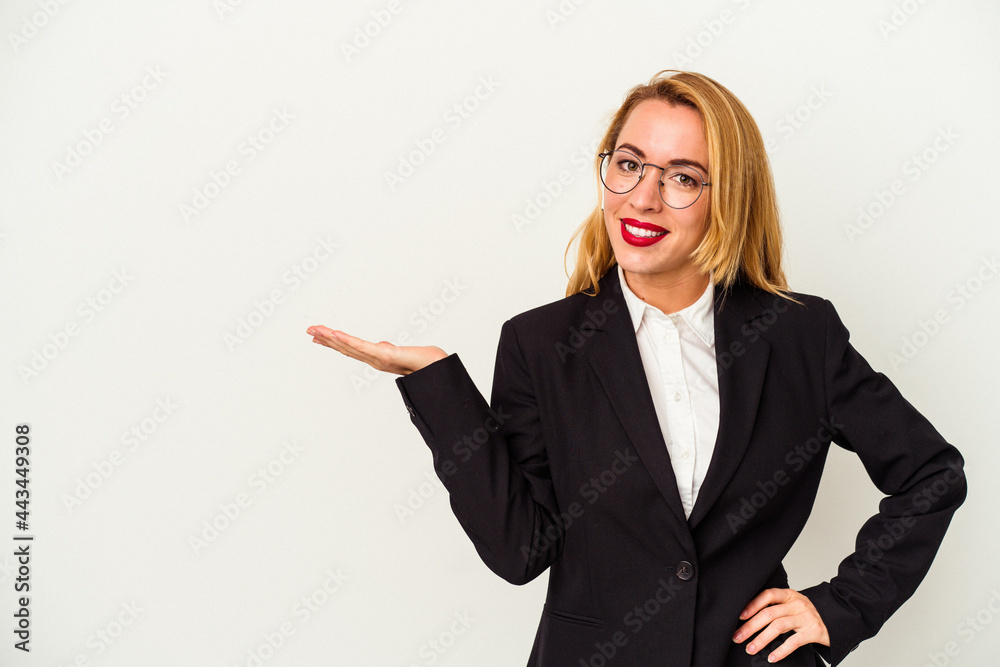 Caucasian business woman wearing a wireless headphones isolated on white background showing a copy space on a palm and holding another hand on waist. Caucasian business woman wearing a wireless headphones isolated on white background showing a copy space on a palm and holding another hand on waist.