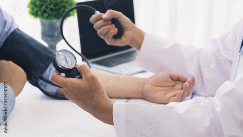 Doctor measuring blood pressure of the patient with sphygmomanometer in the hospital, Medical and health care concepts.