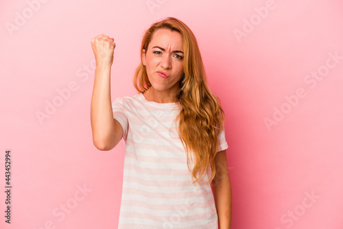 Caucasian blonde woman isolated on pink background showing fist to camera, aggressive facial expression.