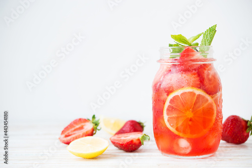Cold summer strawberry lemonade in a jar on a white background, selective focus