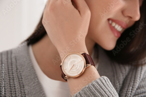 Woman with luxury wristwatch on light background, closeup photo
