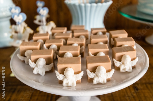 Prato de doces de festa de batizado enfeitados com anjinhos de chocolate branco.