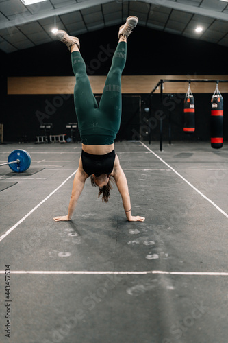 Young woman training on floor in a gym practicing handstand walk