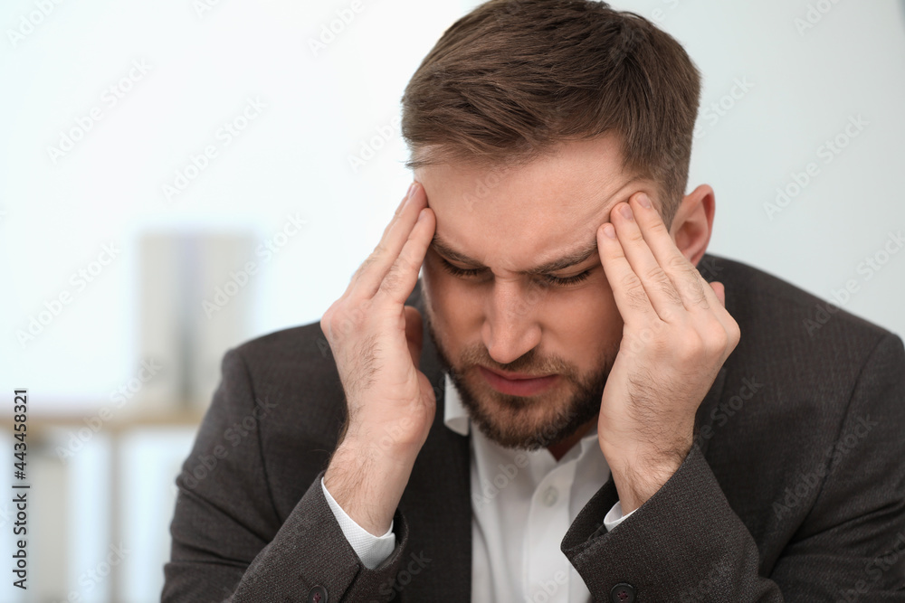 Young man suffering from migraine indoors, closeup Young man suffering from migraine indoors, closeup