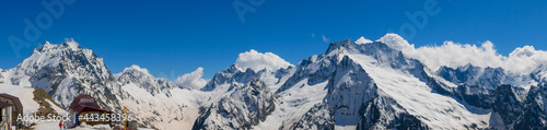Panoramic view from Mount Mussa-Achitara to the Caucasian mountain range. Beautiful high snow-capped mountains with pointed peaks against the blue sky. Dombai, Karachay-Cherkess Republic, Russia © lexosn