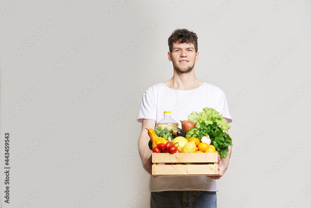 online shopping concept. A man in T-shirt holds a box of fresh food in his hands. Food delivery from the supermarket, from farmers. Delivery during quarantine