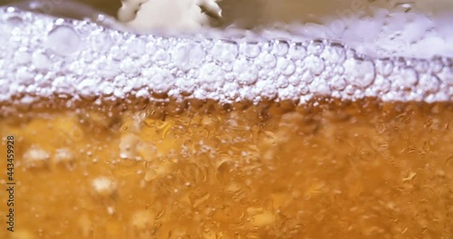 Cold beer is poured into a glass. Cold Light Beer in a glass with water drops. Freshness and froth.