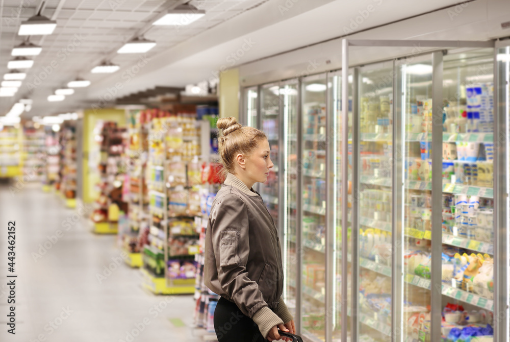 Woman choosing frozen food from a supermarket freezer..