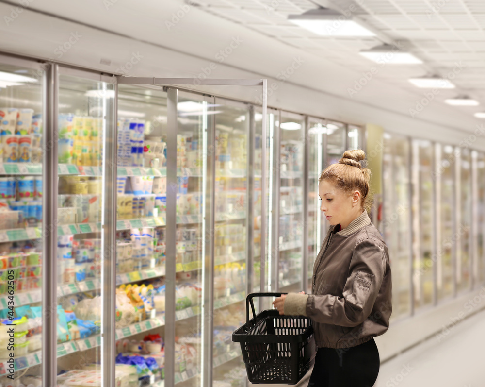 Woman choosing frozen food from a supermarket freezer.. Woman choosing frozen food from a supermarket freezer..