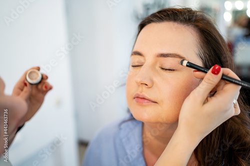 women do make-up  paint the eyelids on the eyes with a makeup brush. 