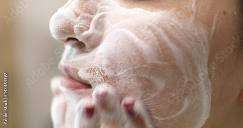 Young woman is washing applying foam cleanser on face. Daily facial skincare procedure. photo