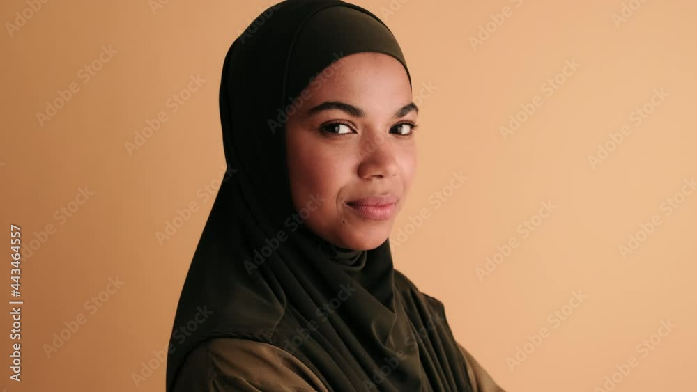 A happy arabian woman is laughing while looking to the camera standing isolated over beige background A happy arabian woman is laughing while looking to the camera standing isolated over beige background