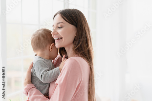 Smiling lovely mother with her little small son daughter. Young nanny childminder taking care of infant, newborn baby. Family moments.Motherhood and childcare. Adoption and IVF concept