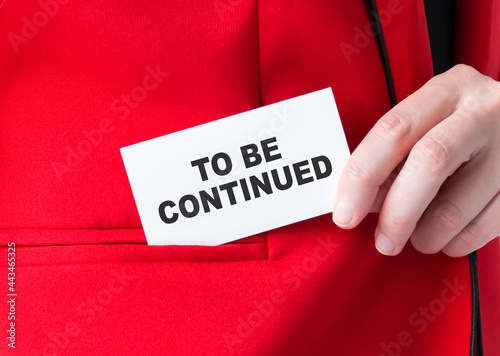 a woman holds a card with text TO BE CONTINUED puts her in the pocket of her jacket. business concept