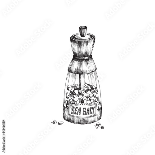 Kitchen glass saltshaker with pieces of sea salt and label with lettering.
