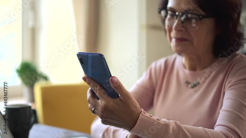 Old woman read funny news joke on phone and laugh. Mature lady has hilarious emotional reaction
