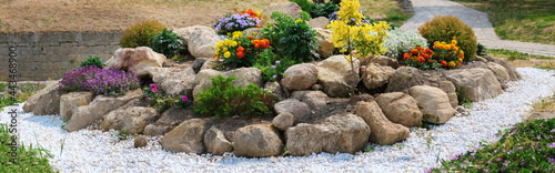 Obraz na plátně panorama round flower bed of flowers and stones
