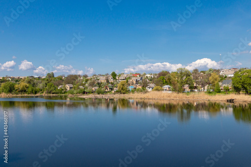 green coast of a beautiful small river with white clouds in reflection