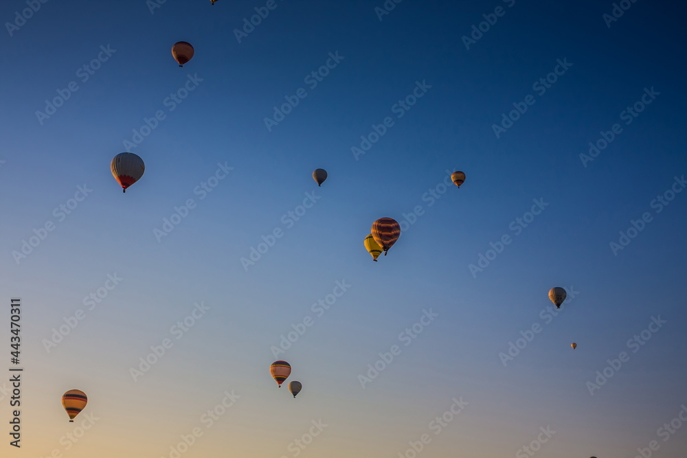 Hot air balloons flying over the valley at Cappadocia, Turkey. Goreme Balloon Festival. Beautiful hot air balloons take off at sunrise. Hot air balloons in the blue sky Hot air balloons flying over the valley at Cappadocia, Turkey. Goreme Balloon Festival. Beautiful hot air balloons take off at sunrise. Hot air balloons in the blue sky