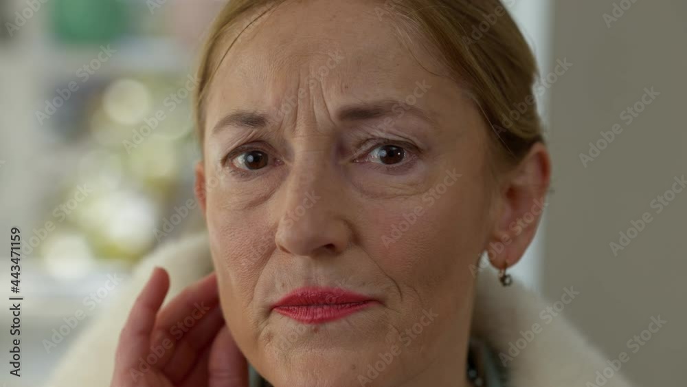 Close-up wrinkled face of middle aged Caucasian woman looking at camera. Headshot portrait of sad desperate elegant wealthy lady touching wrinkles. Frustration and aging