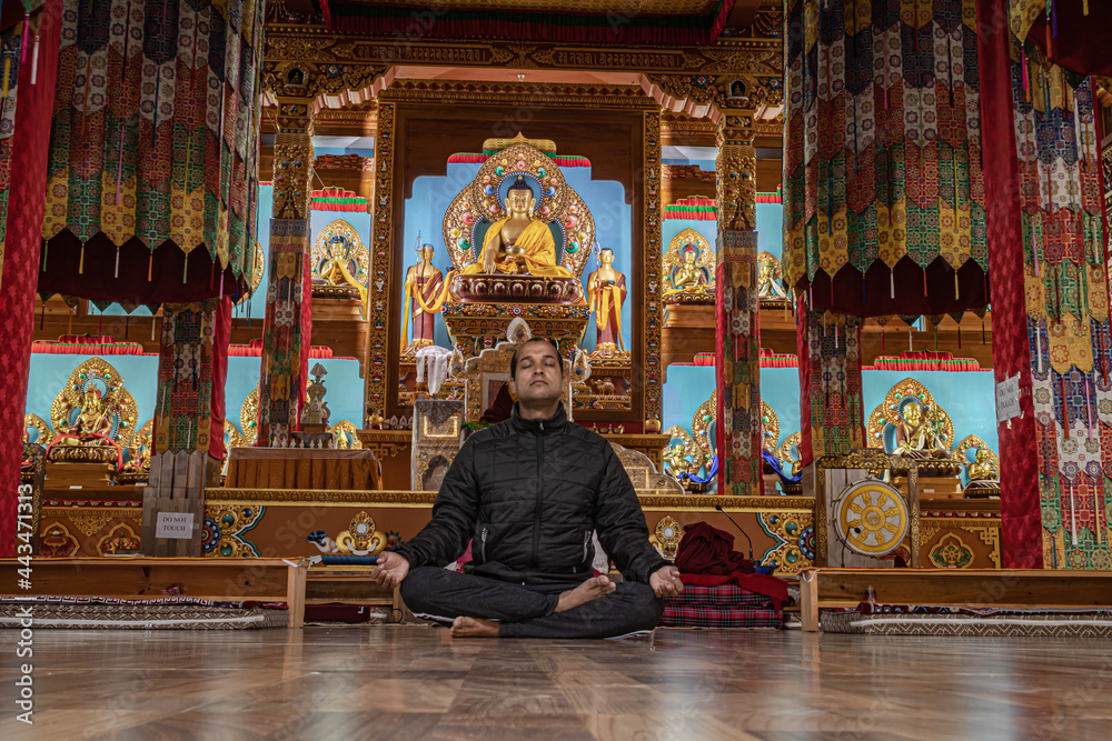 man meditating isolated inside buddhist monastery at morning from low angle