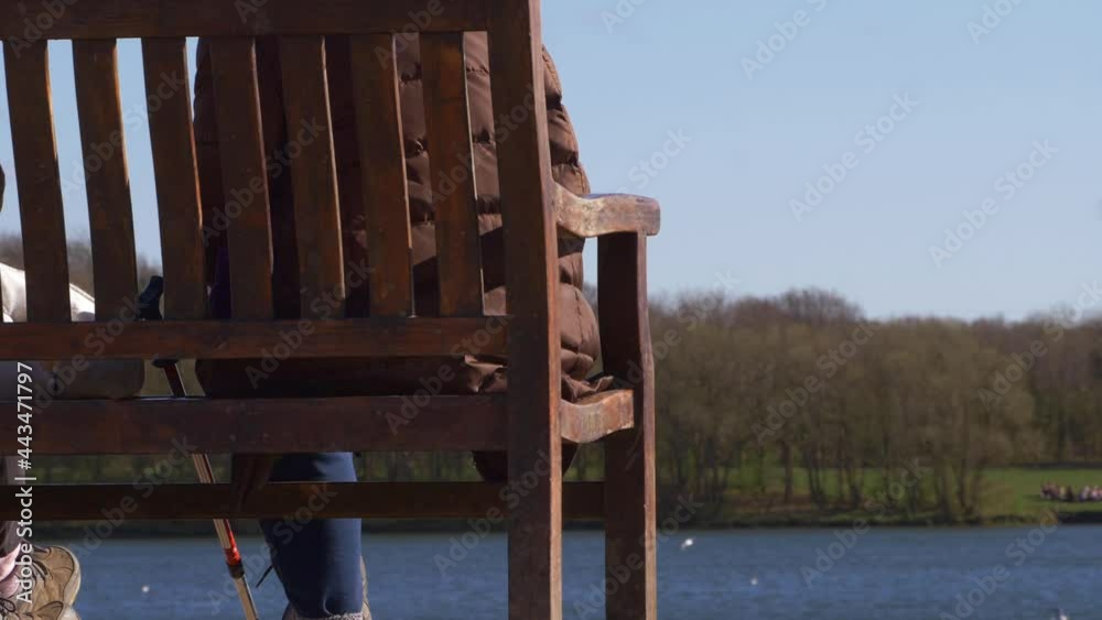 Enjoying view of lake sitting on a wooden bench Enjoying view of lake sitting on a wooden bench