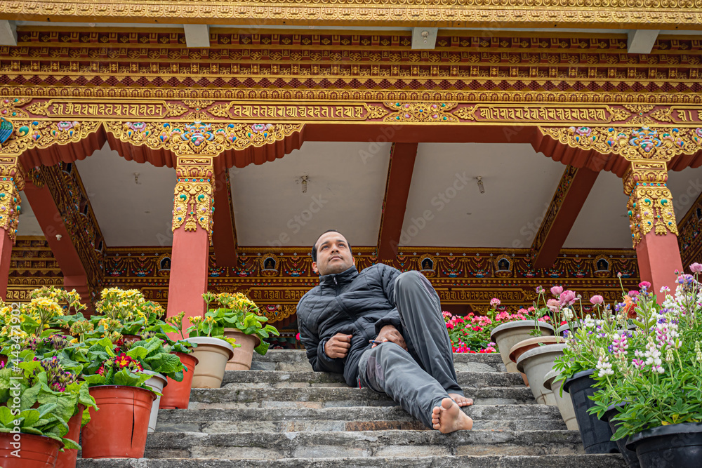 young man sitting at the stair of buddhist monastery at morning from low angle young man sitting at the stair of buddhist monastery at morning from low angle