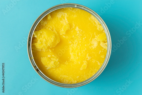 View from above of can full of Ghee butter on blue background.
