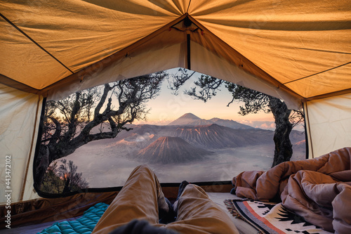 Traveler man relaxing and taking the view of Bromo active volcano inside a tent in the morning