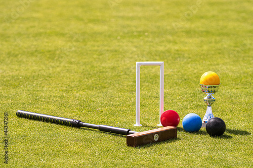 Vászonkép a set of colored balls, a hammer and a winners prize at the croquet wicket on th