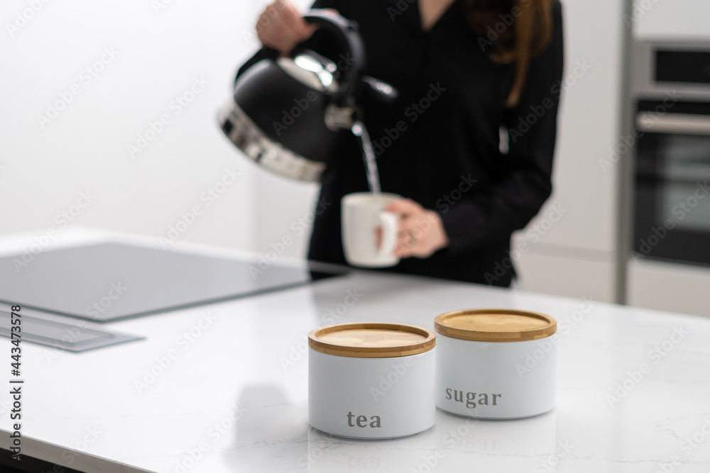 Woman pouring hot water from kettle into mug