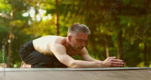 Man practicing yoga.Yogi snading on knees with hands stretched in front.Guy moving head up and down photo