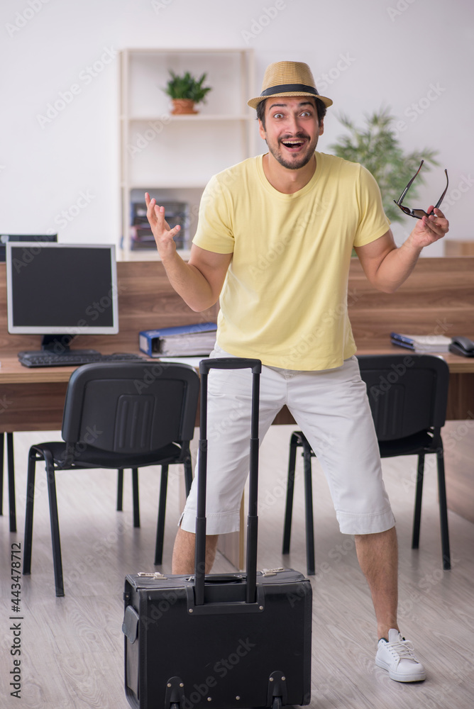 Young male employee preparing for trip at workplace Young male employee preparing for trip at workplace