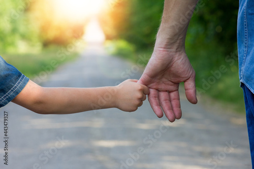 the parent holds the hand of a small child